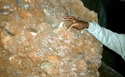 南アフリカ・スタークフォンテン洞窟Sterkfontein Cave ガイドが指さす角礫岩に残された猿人化石部分